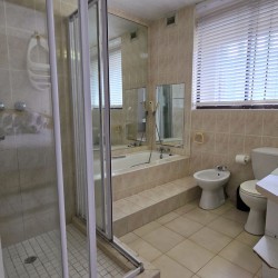 Large ensuite bathroom with walk-in shower and a bath off of the main bedroom in C Front 11 self-catering penthouse.