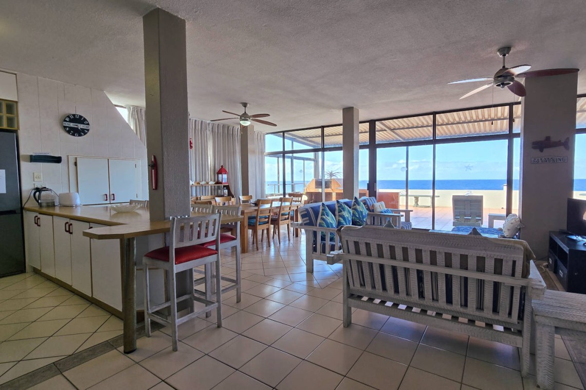 The bright open-plan lounge and kitchen with large windows overlooking the Indian Ocean at C Front 11