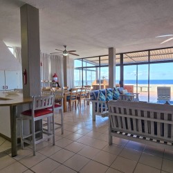 The bright open-plan lounge and kitchen with large windows overlooking the Indian Ocean at C Front 11