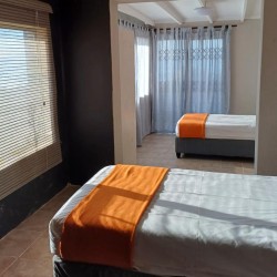 Sea Park House, the left wing downstairs bedroom with door to patio, garden and swimming pool in holiday home with sea view in KwaZulu Natal