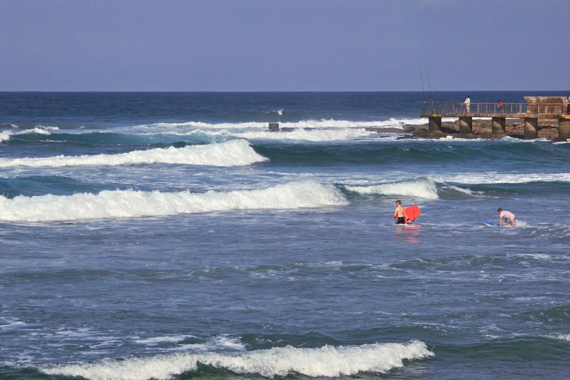 Children body-boarding at Uvongo Beach, just steps from Topanga 25 – a beachfront holiday rental in Uvongo ideal for families looking for fun in the surf.