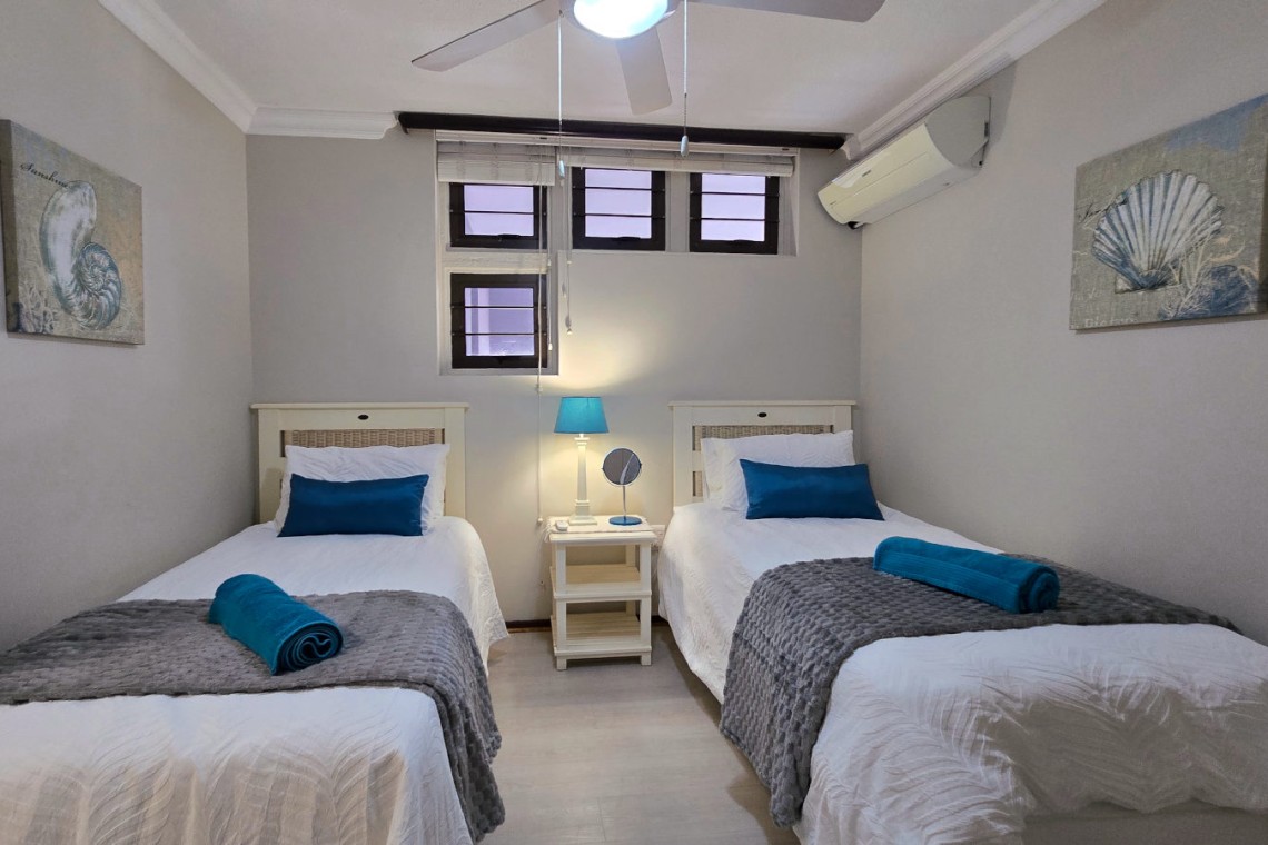 Third bedroom with two singles, air‑conditioning and ceiling fan