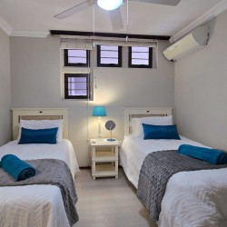 Third bedroom with two singles, air‑conditioning and ceiling fan